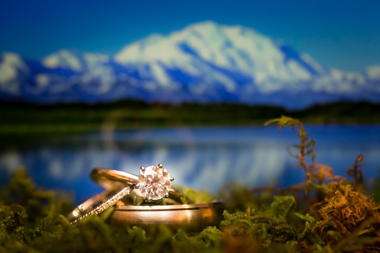 wedding rings sit in moss with Wonder Lake , Denali National Park AL in background