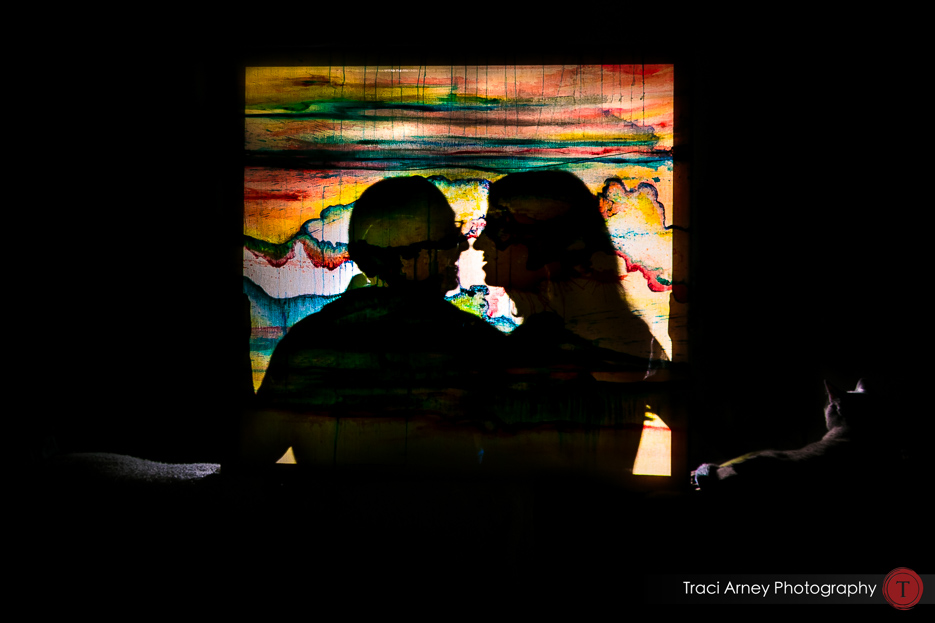 Engagement session in Greensboro, NC, bride and groom silhouetted behind colorful painting.