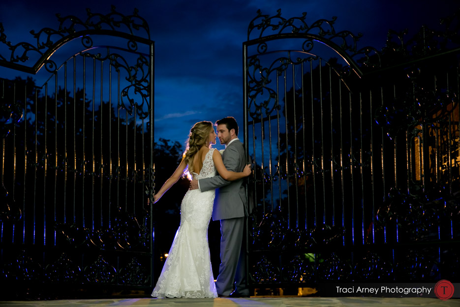 bride and groom between wrought iron gate against an intense blue night sky. Revolution Mills wedding.