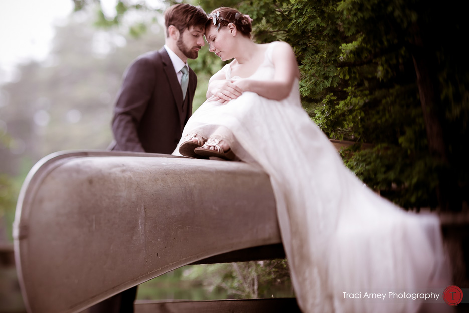 bride and groom sit on top of canoe in Camp Pinnacle outdoor campground wedding in Asheville, NC