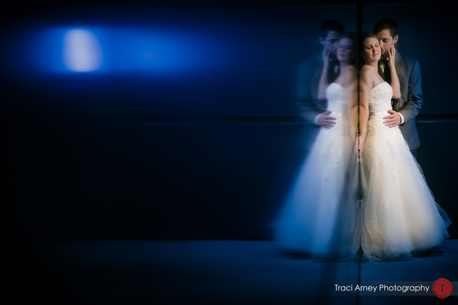 bride and groom embrace in blue lit hallway at baseball stadium